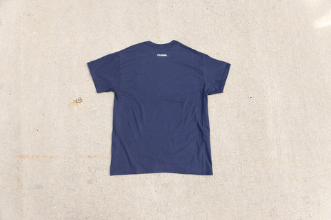 A navy blue short-sleeve t-shirt laid flat on a textured concrete surface, viewed from the back. A small white 'Models.' brand logo is printed near the upper neckline.