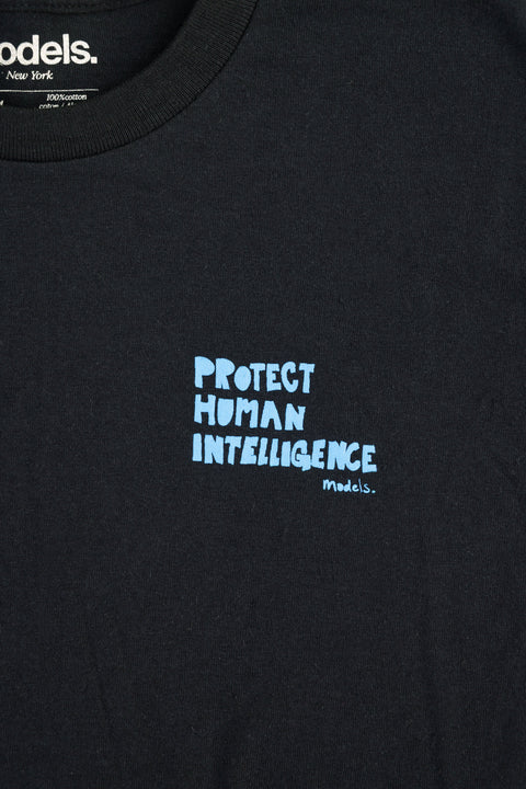 Close-up of a black crewneck t-shirt featuring the slogan 'PROTECT HUMAN INTELLIGENCE' printed in light blue text on the chest, with the 'models.' brand name visible both on the chest print and inside the collar label.