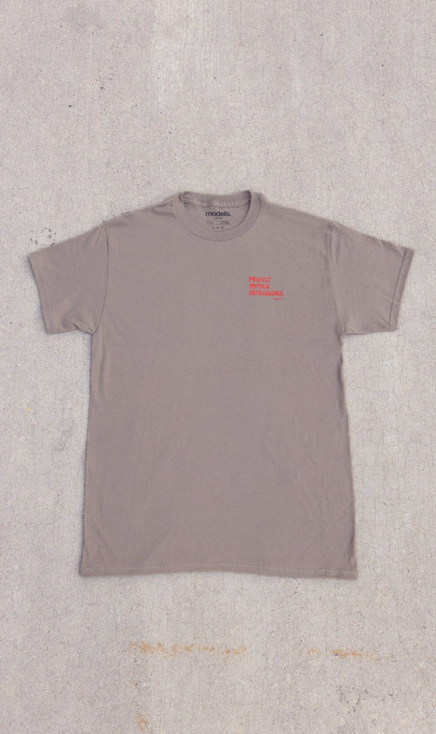 A Brown Savana short-sleeve t-shirt with a small red graphic on the left chest, laid flat on a textured concrete surface.